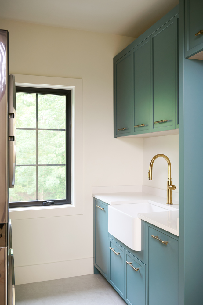 Bright laundry space with gold faucet and built-in cabinetry in a custom home by DesignLab in Loudoun County, VA