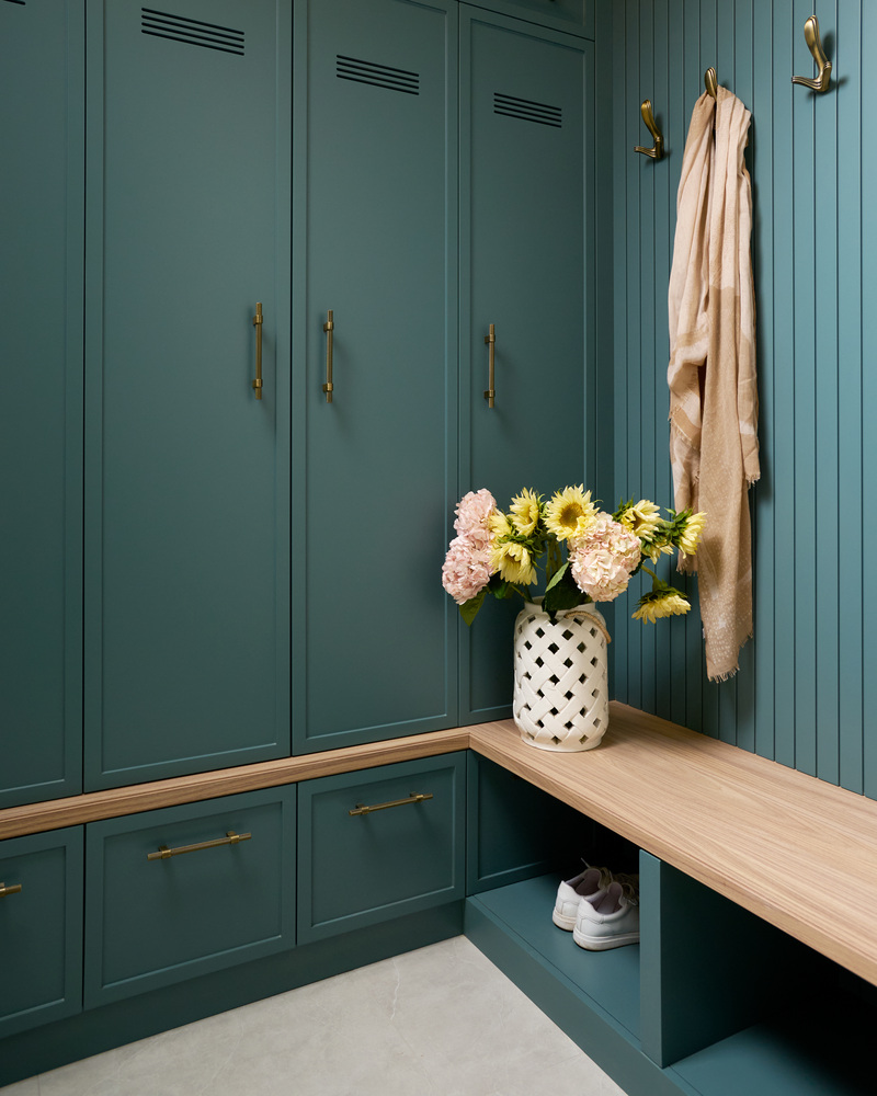 Custom home mudroom in Bethesda, MD with brass hooks, built-in storage, and a wooden bench by DesignLab