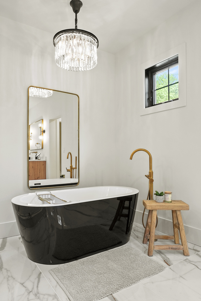 Freestanding black soaking tub with chandelier in Washington, DC bathroom by DesignLab
