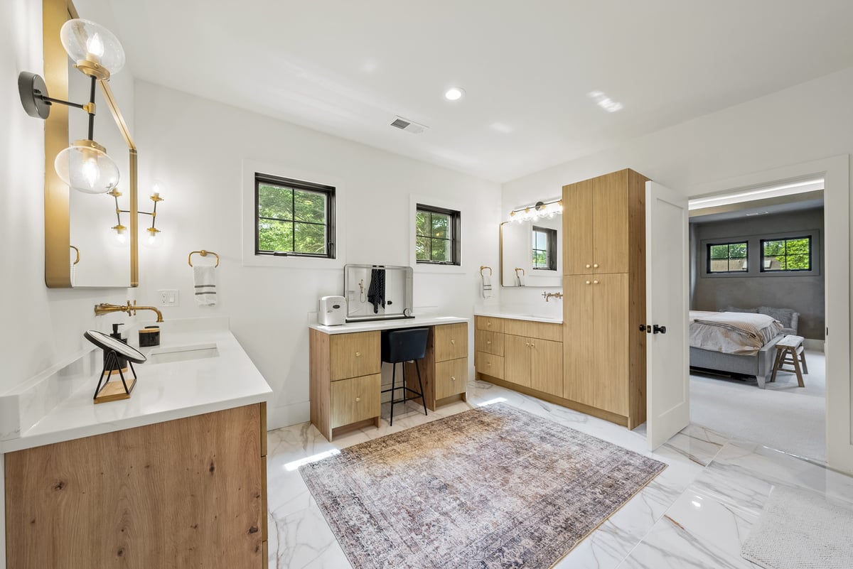 Primary ensuite with double vanities and light wood vanities