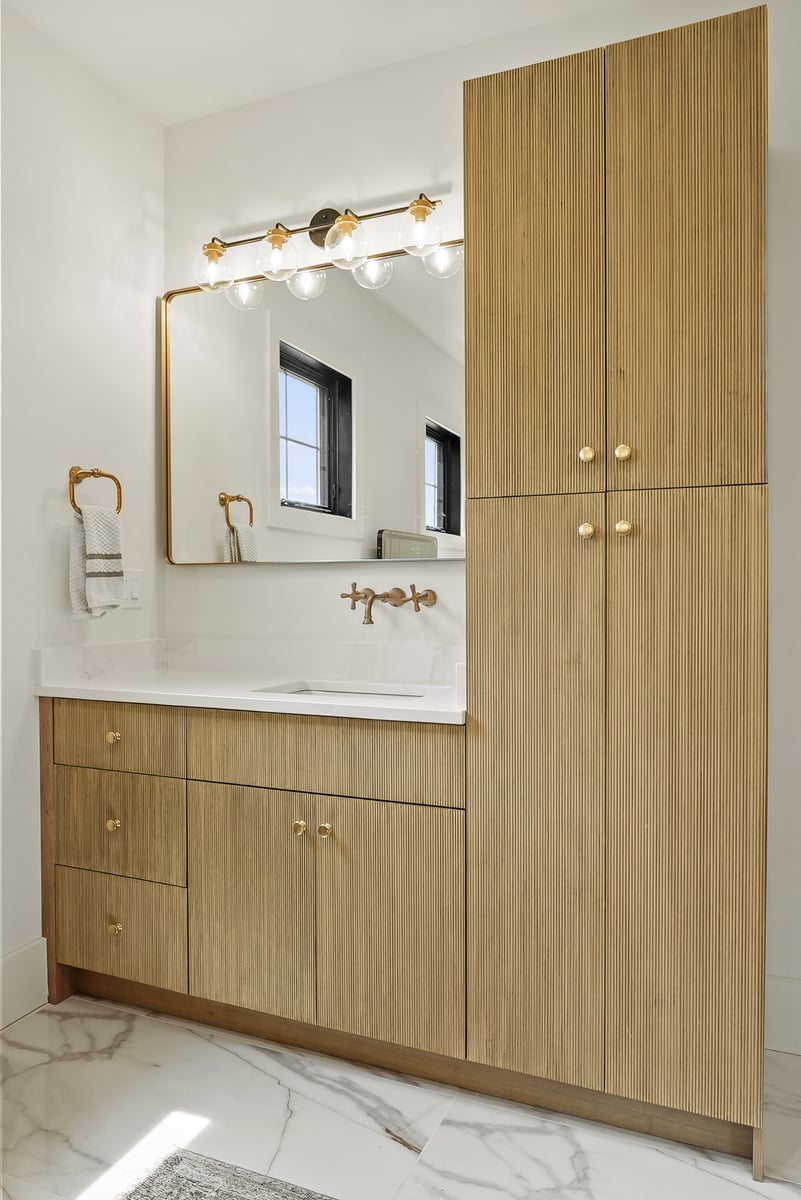 Remodeled bathroom vanity with light wood vanity and gold finishes in Vienna, VA