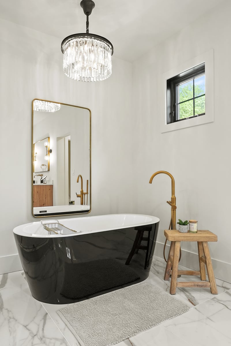 Remodeled bathroom with black soaking tub, gold hardware, and marble flooring in Vienna, VA