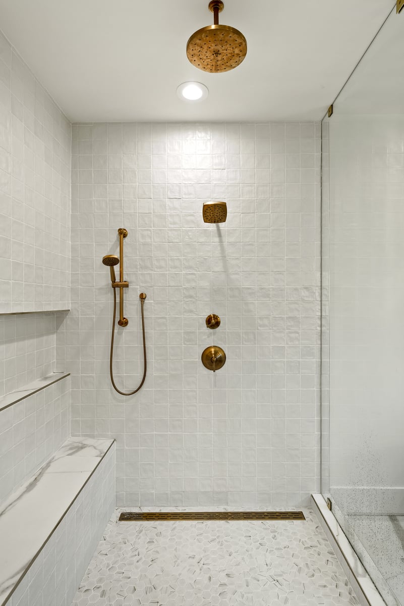Walk-in shower with white tile walls and gold hardware in Vienna, VA, by DesignLab