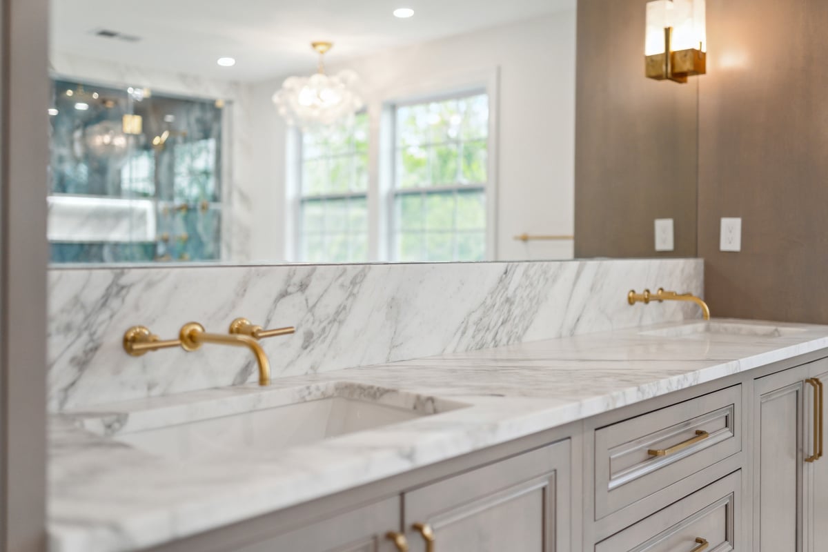 Close-up of marble double sink vanity with gold fixtures by DesignLab in Metro Washington