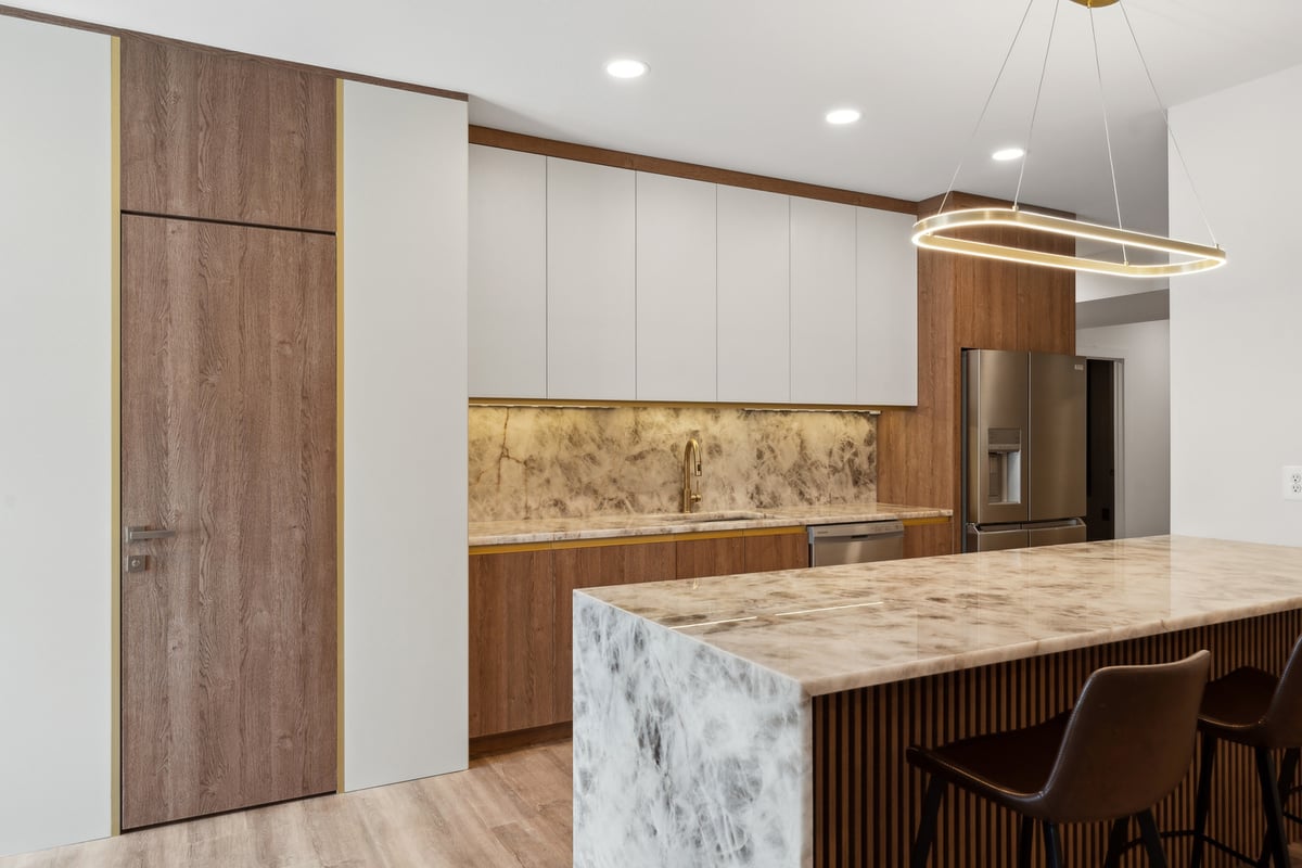 Remodeled kitchen with waterfall island and wood paneled wall in Metro DC