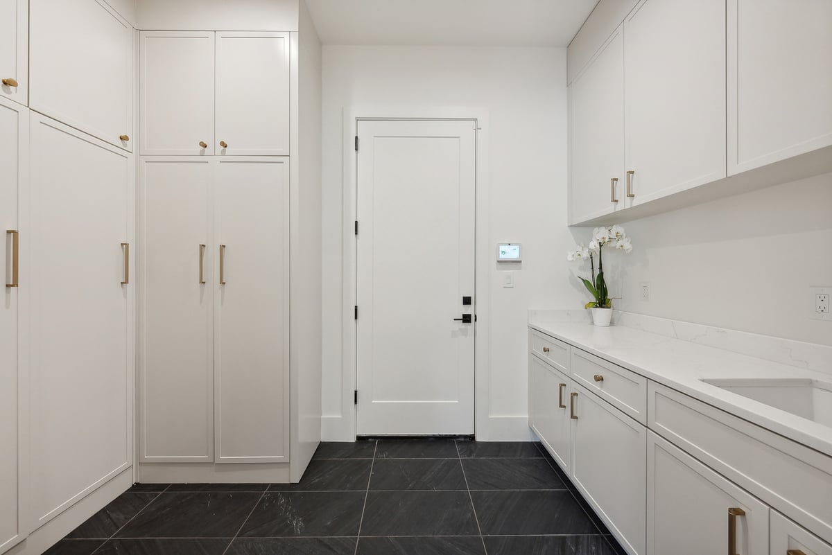 Elegant utility room with white cabinetry and black tile floors in a DesignLab custom home in McLean, VA