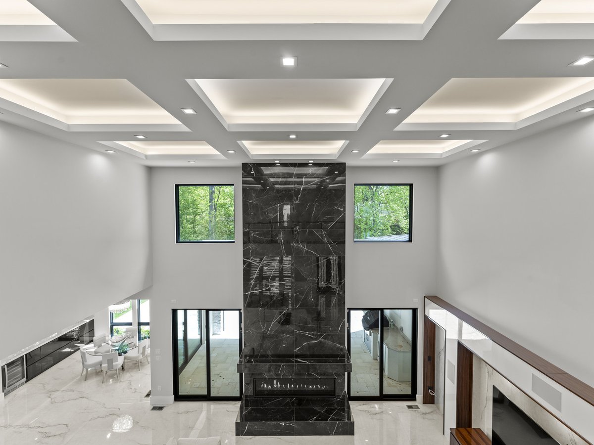 Dramatic two-story living room with floor-to-ceiling marble fireplace in a DesignLab custom home in Potomac, MD