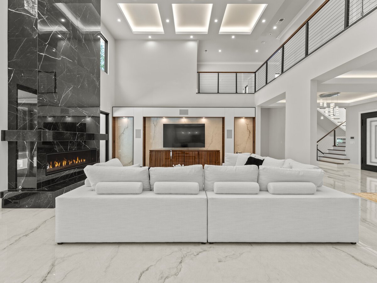 High-ceiling living room with statement fireplace and recessed lighting in a DesignLab home in Chevy Chase, MD