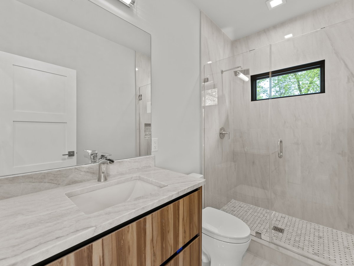 Light-filled bathroom with wood cabinetry and marble finishes in a DesignLab residence in Chevy Chase, DC