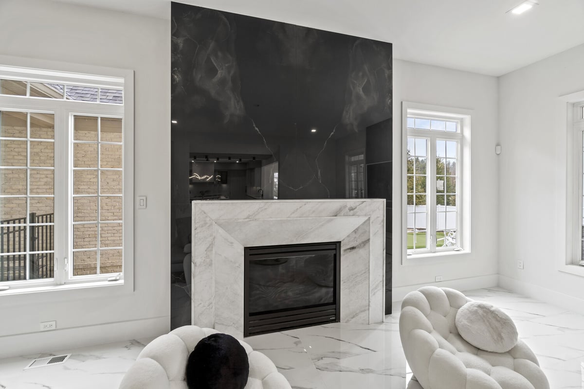 Contemporary fireplace design with black stone accent wall and white marble surround by designlab in Northern Virginia
