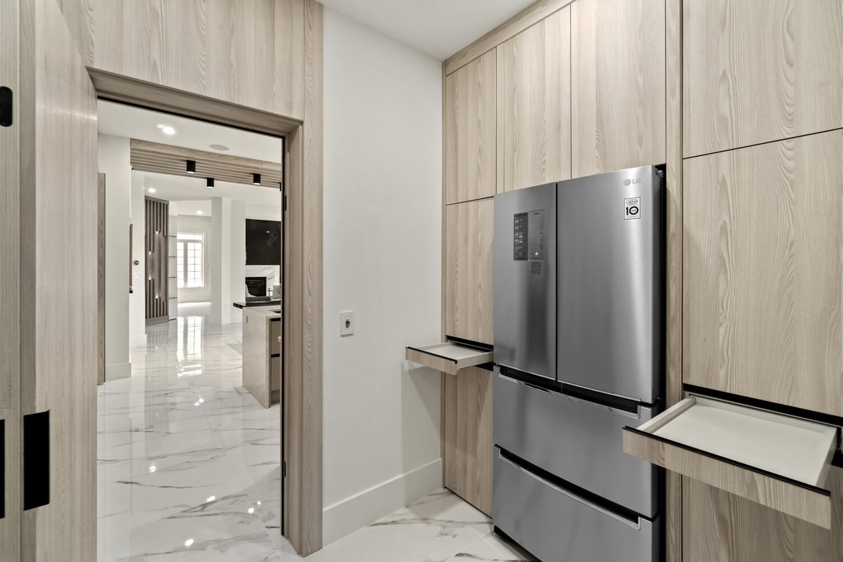 Kitchen walk-through with light wood cabinetry and stainless steel fridge by designlab, Northern Virginia