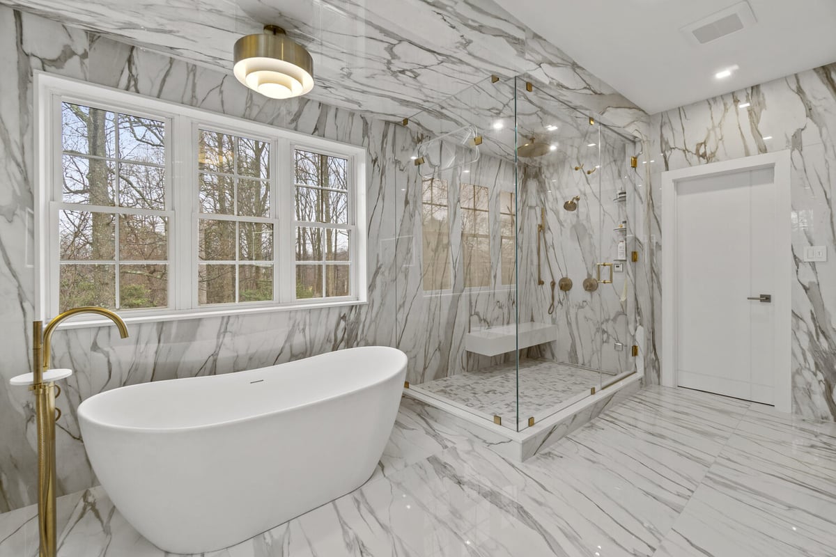 Large glass-enclosed shower with freestanding tub in marble bathroom by DesignLab in Metro Washington