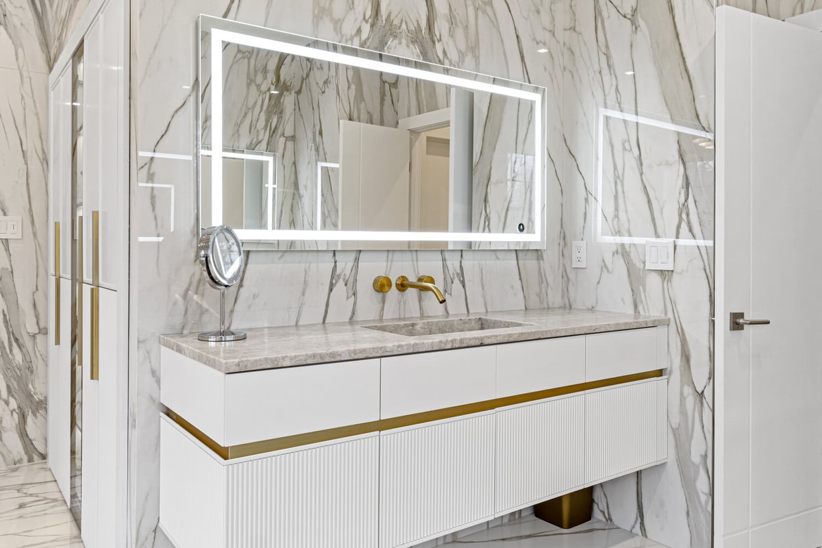Luxury bathroom vanity with backlit mirror and marble walls in a DesignLab custom home in Metro Washington