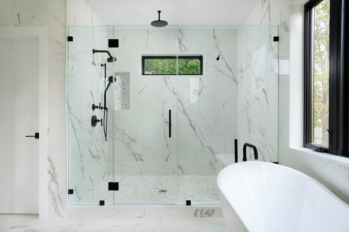 Frameless glass shower with black fixtures in a luxury bathroom by DesignLab in Metro Washington