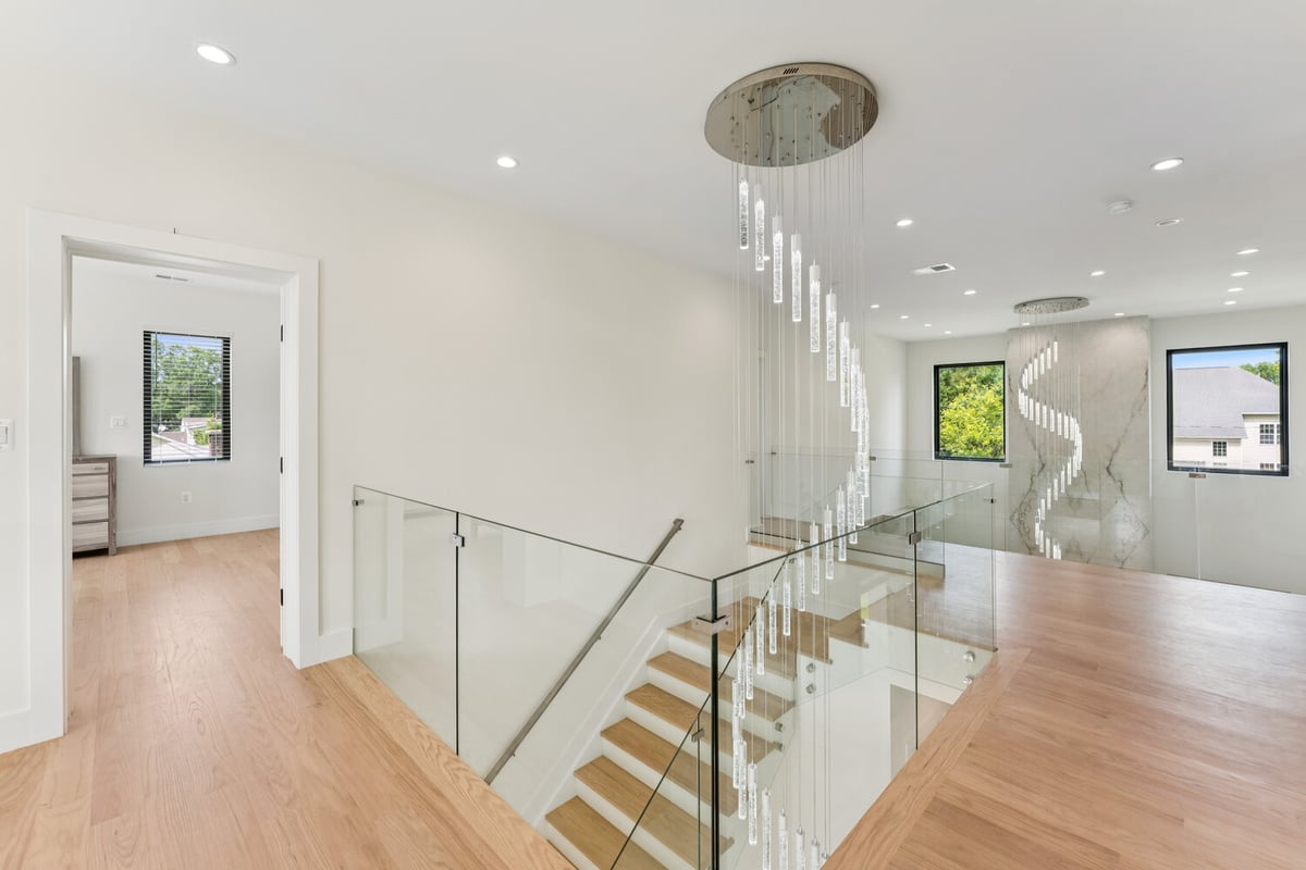 Modern staircase with glass railing and spiral pendant light by DesignLab in Vienna
