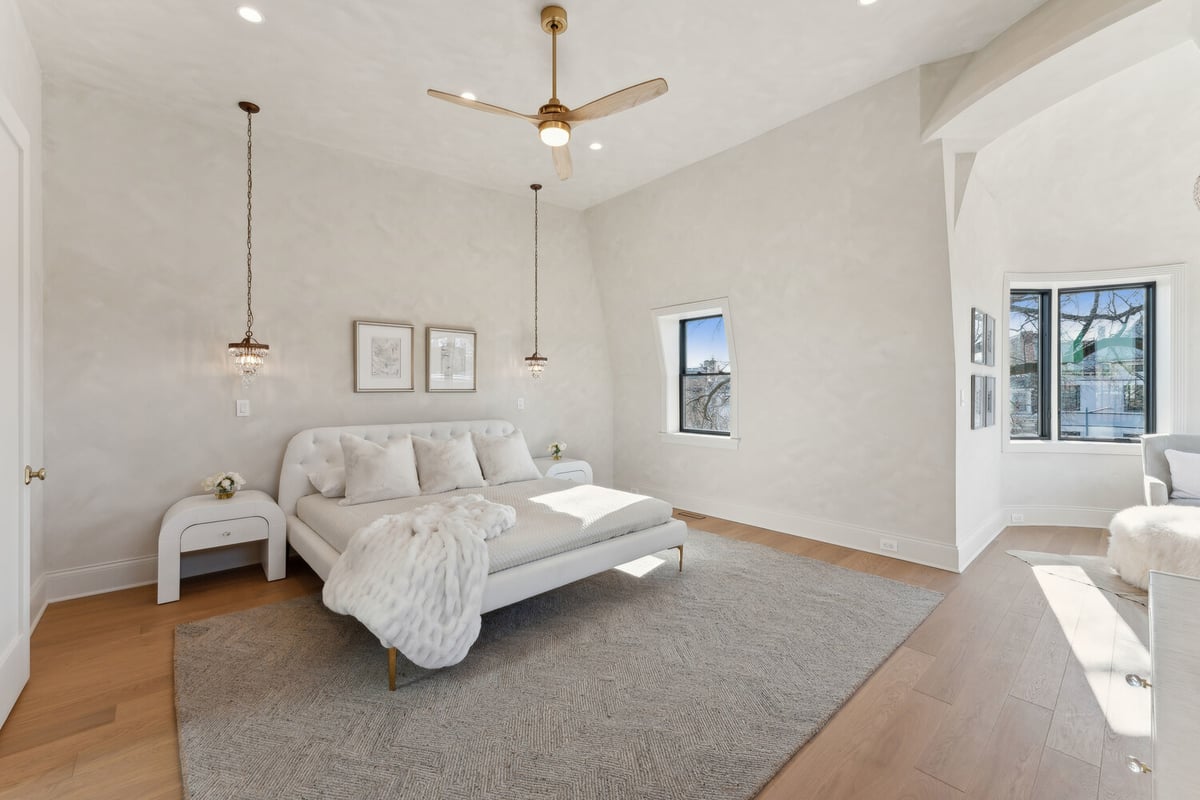 Spacious primary bedroom with plush bed and ceiling fan in a DesignLab custom home in Rhode Island