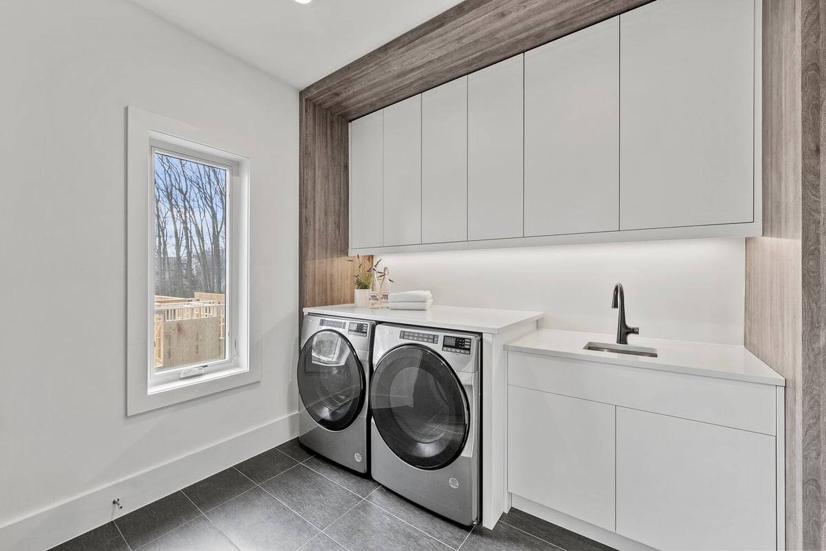 Bright laundry room with front-load washer and white cabinetry in a custom home by DesignLab in Washington, DC