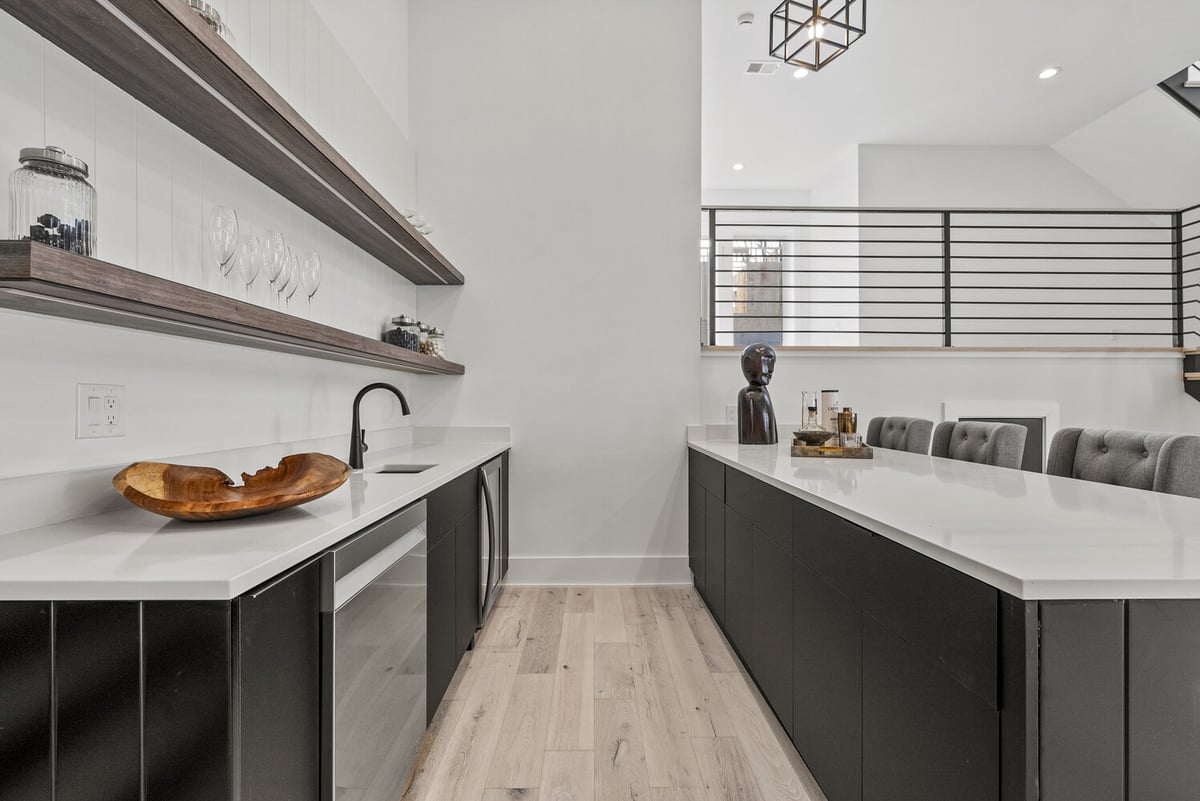Dual-perspective view of modern wet bar with shelves and seating in River Oaks home by DesignLab