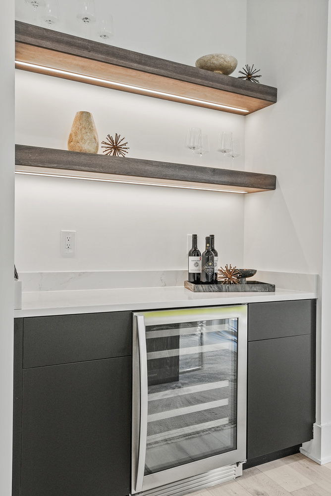 Modern bar area with wine fridge and floating shelves by DesignLab in Arlington, VA custom home